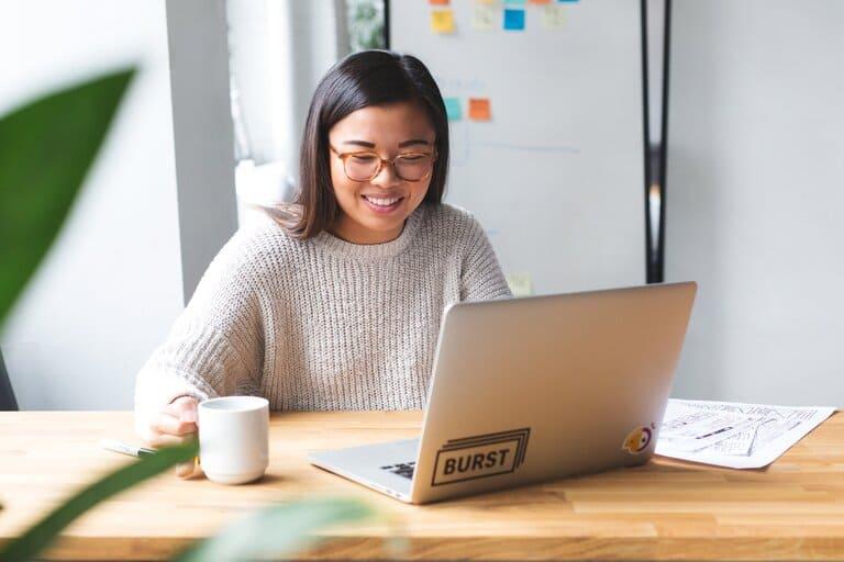 woman sitting at a table looking at the screen of her laptop